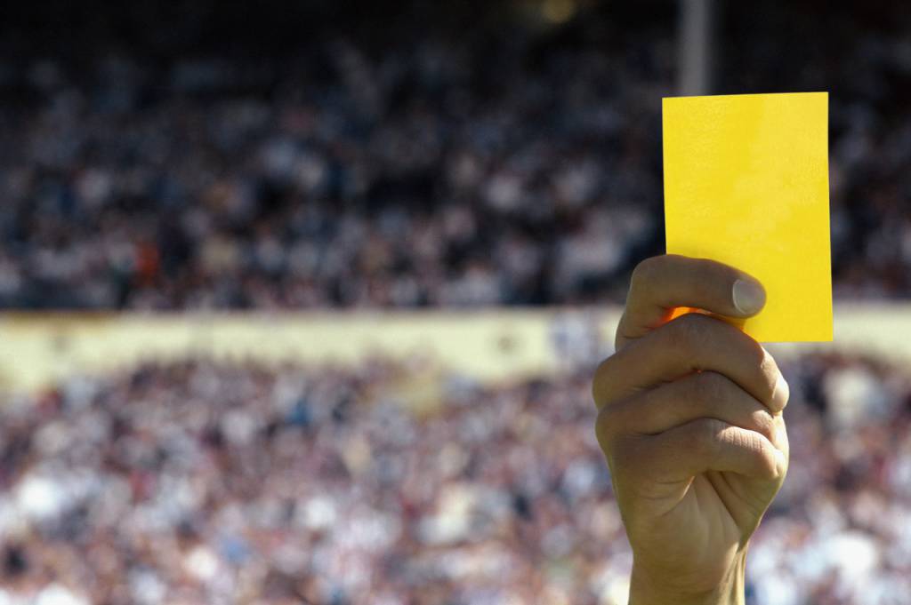 Hand holding up a yellow card
